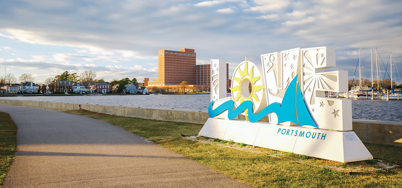 Portsmouth Virginia waterfront with LOVE sign at sunset, featuring scenic views of the Elizabeth River and historic buildings in the background.